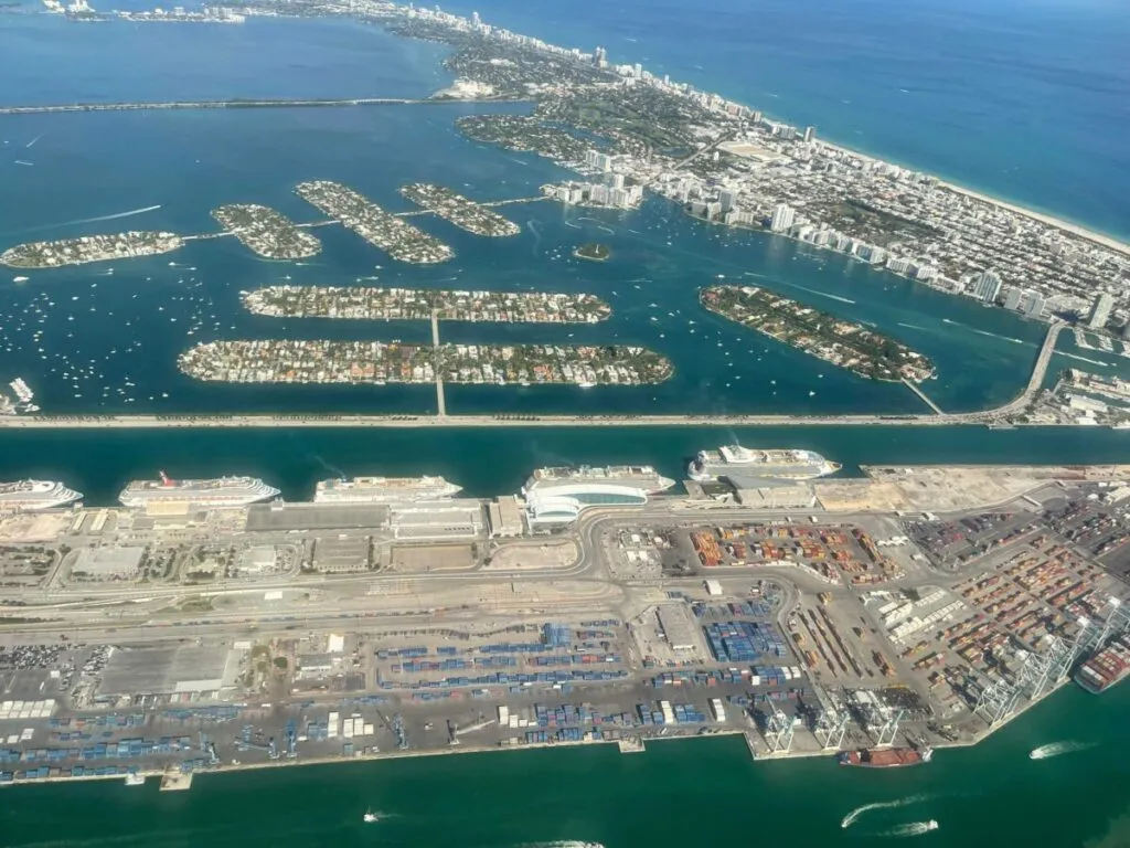 Vista aérea de PortMiami con barcos de carga y cruceros, mostrando su expansión estratégica hacia Fisher Island en Miami
