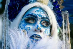 Personas disfrazadas con trajes de Catrina durante la Carrera de Catrinas en Miami, entre flores y altares coloridos