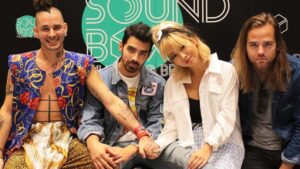 Joe Jonas y DNCE sobre el escenario durante un show en vivo, reflejando la energía y estilo característico del grupo.