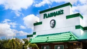 Lata de Joe’s Pale Ale sobre una mesa con comida típica de Flanigan’s, representando su llegada a tiendas de Florida.