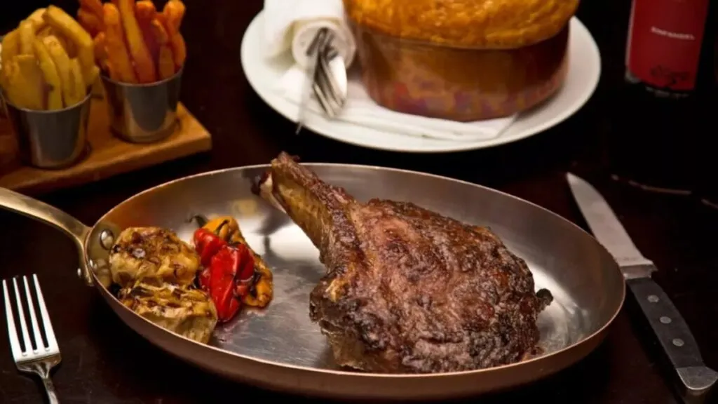 Chef de steakhouses preparando un corte premium en una parrilla moderna dentro de un elegante restaurante de Miami.