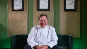 Retrato editorial de Norman Van Aken en cocina moderna con elementos que evocan sabores locales y cultura culinaria de Miami