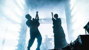 El dúo argentino Peces Raros en un escenario al aire libre con luces verdes y azules durante su presentación en Miami.