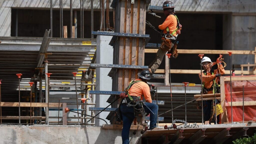 Trabajadores migrantes llevando a cabo labores de construcción en Miami durante un proyecto urbano activo
