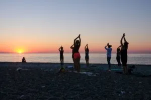 Personas practicando yoga en la playa de Miami al atardecer durante New Moon Beach Yoga