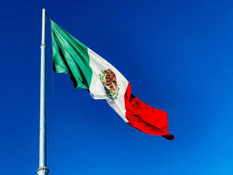 Bandera de México ondeando en ceremonia cívica que refuerza la identidad nacional y la unión social