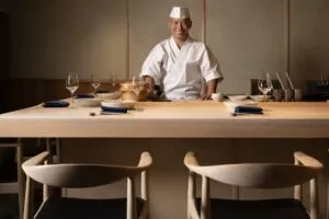 Chef japonés en mostrador de madera hinoki sirviendo sushi en restaurante de lujo en el Design District de Miami