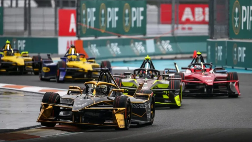 Fórmula E Miami con monoplazas eléctricos compitiendo bajo lluvia en el Hard Rock Stadium durante el ePrix ganado por Mitch Evans