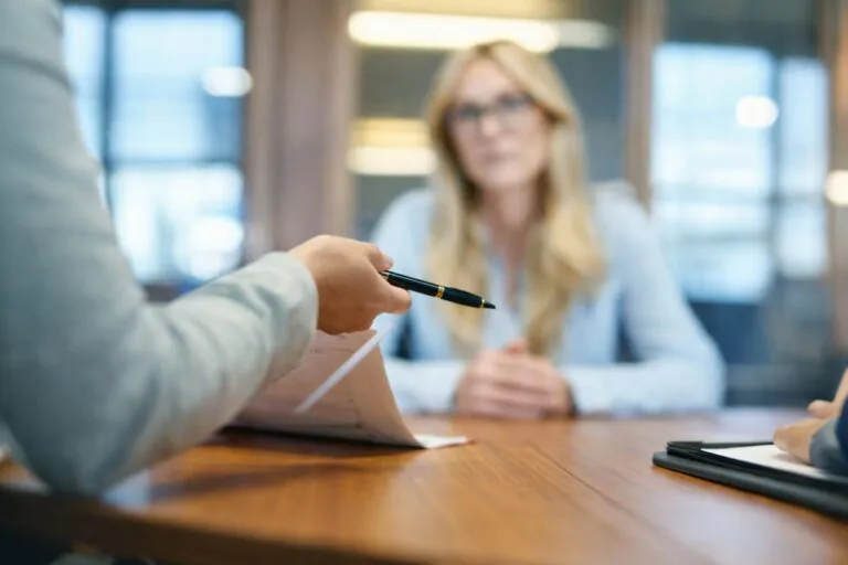 Reunión institucional en mesa de madera donde se revisan documentos oficiales con luz natural en ambiente profesional.