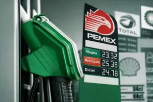 Manguera de gasolina verde en estación PEMEX en México mostrando precios de Magna, Premium y Diesel
