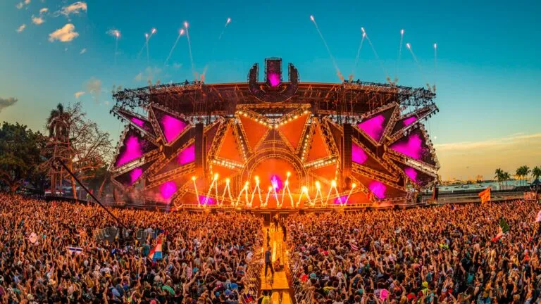 DJ tocando música electrónica frente a público en club nocturno de Miami con luces y ambiente festivo