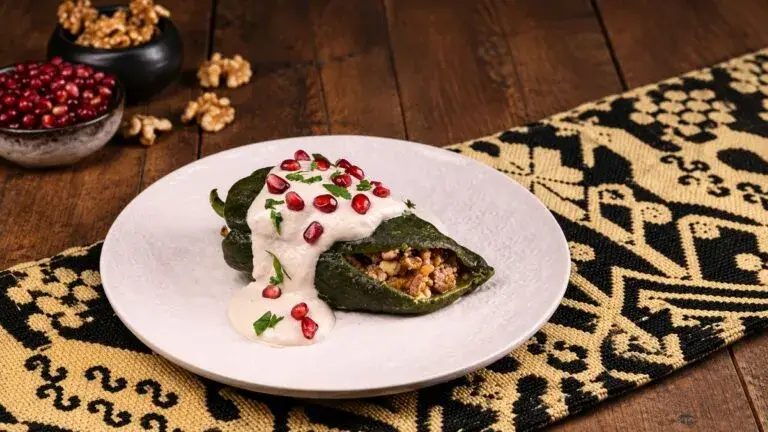 Chile en nogada elaborado con ingredientes de temporada y servido en una mesa tradicional mexicana.