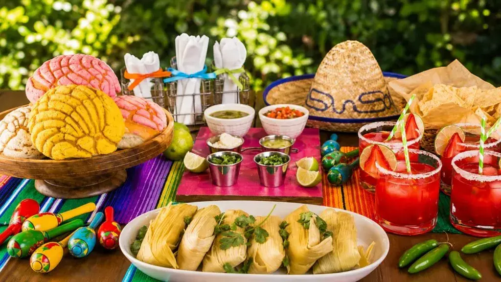 Mesa preparada para una noche mexicana con comida, música y decoración del 15 de septiembre.