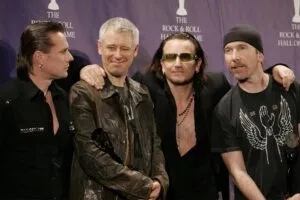 Banda de rock U2 durante una presentación musical con iluminación de concierto y público.