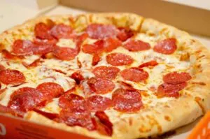 Pizza preparada para comida a domicilio junto con antojitos mexicanos y aplicaciones de entrega digital.